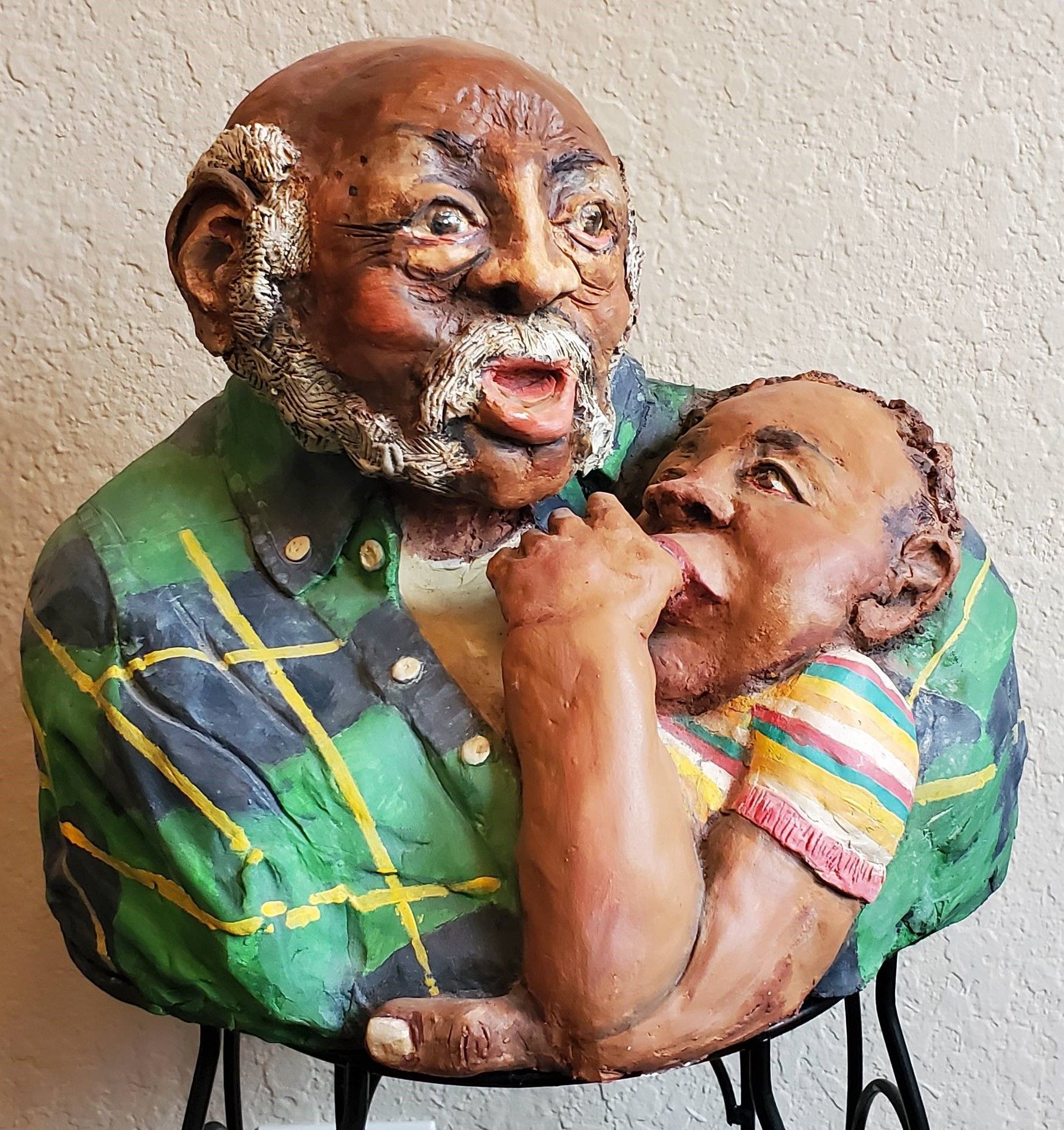 A sculpture of a grandfather holding his grandchild while she sucks her thumb